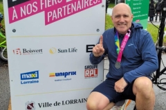 Coureur assis portant une médaille devant le panneau des partenaires