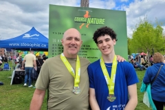 Deux participants portant des médailles devant le panneau de course
